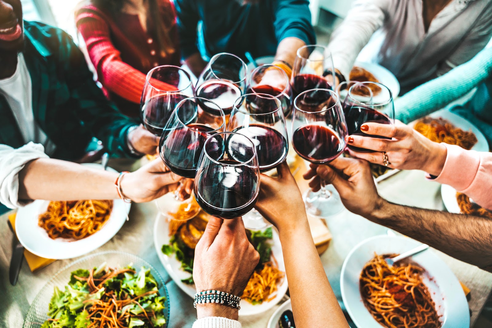 Friends raising wine glasses over a table of food
