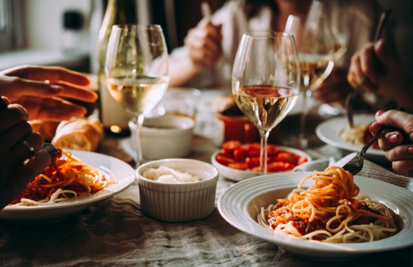 Italian dinner table set with pasta and wine glasses