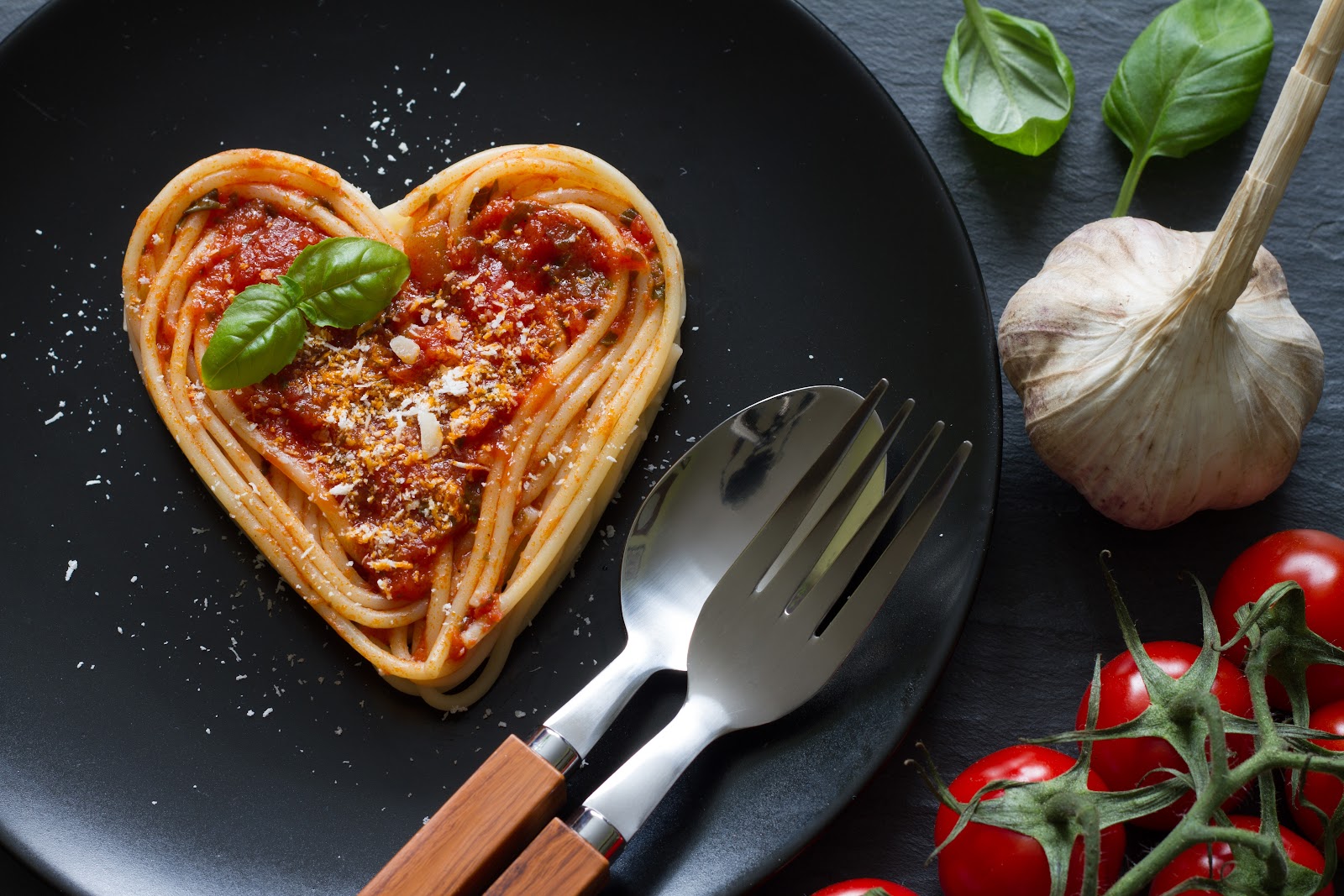 Heart-shaped Italian lasagna in a pan with basil, garlic and tomatoes