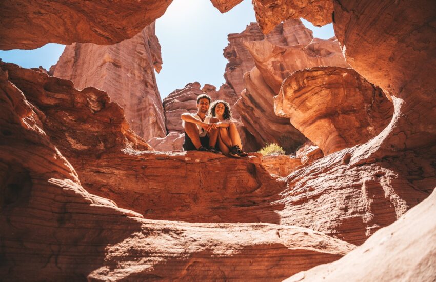 Two visitors sitting inside a red rock arch in Sedona