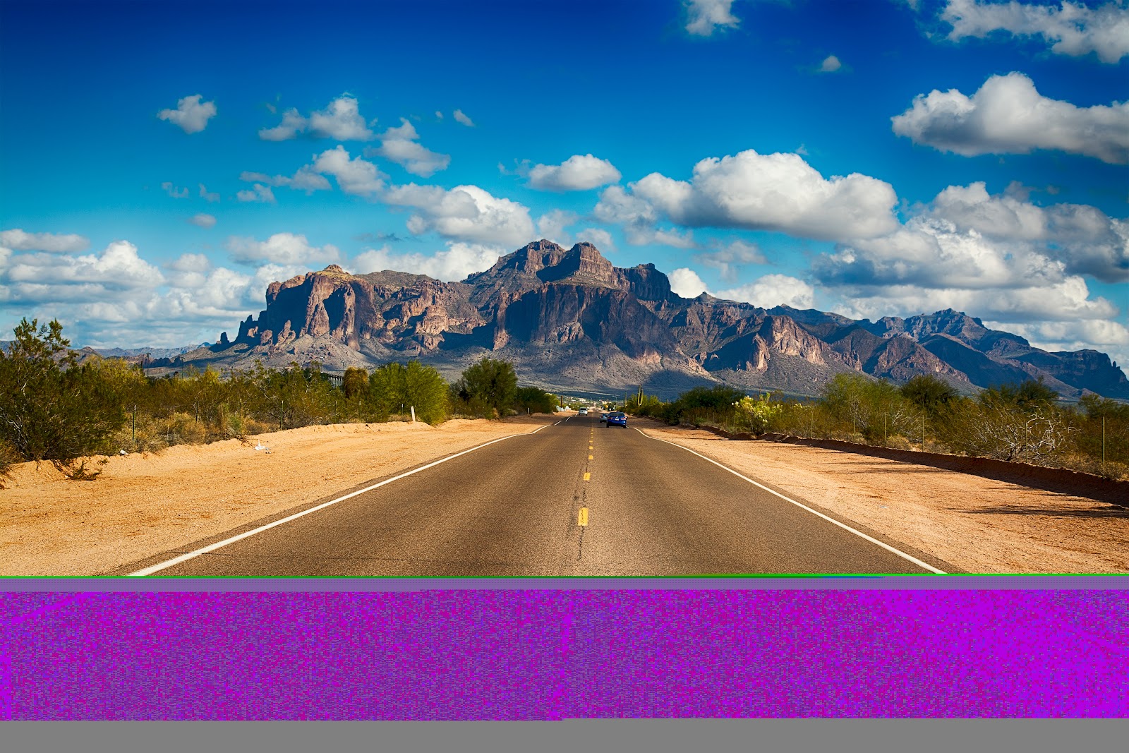 A long, empty Arizona highway leading toward desert mountains, the kind of drive that links Phoenix, Sedona and the Grand Canyon