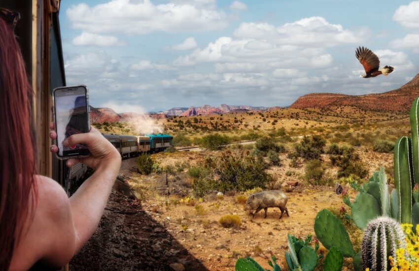 Sedona day trips: a passenger photographing red cliffs from the open-air car of the Verde Canyon Railroad